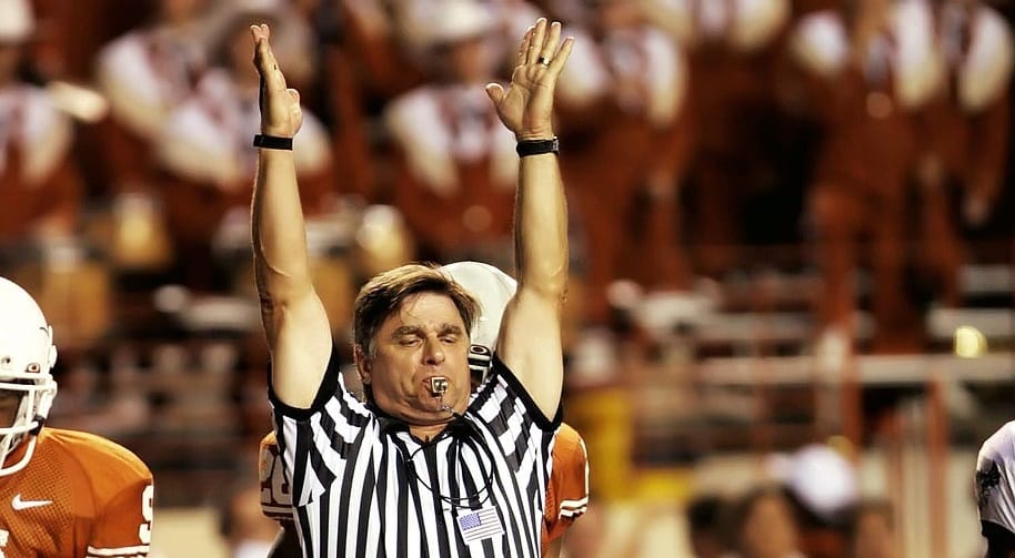 Image of a referee blowing his whistle and signalling a touchdown at a University of Texas football game